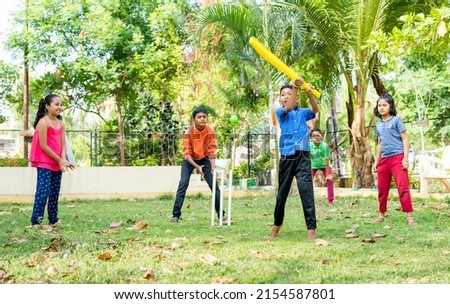 young kid running by hitting the ball while playing cricket at park for scoring - conept of childhood physical activities, vitality and entertainment Royalty-Free Stock Photo #2154587801