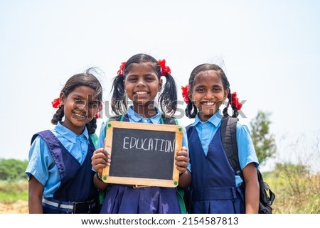 group of teenage Village girl kids in school uniform holding slate with education writings looking at camera - concept of development, education and girl kid development Royalty-Free Stock Photo #2154587813
