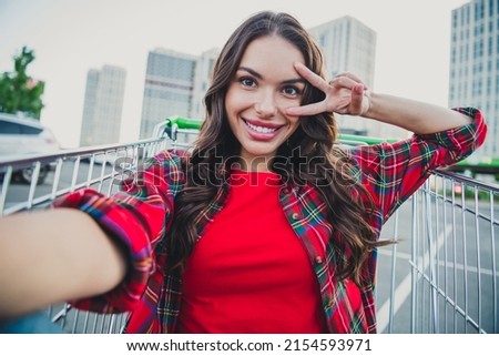 Self-portrait of attractive cheerful funky girl sitting in cart having fun on parking showing v-sign rest relax outdoors