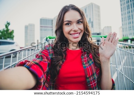 Self-portrait of attractive trendy cheerful carefree girl sitting in cart having fun on parking waving hello outdoors