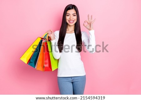 Photo of cool millennial brunette lady hold bags show okey wear simple cloth isolated on pink color background