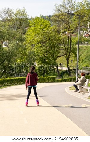 Small girl rollerblading in a park. Recreation, leisure, hobby and sport concept. 