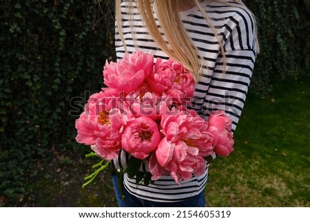 Happy woman holding pink peonies in her hands. The florist girl collected a bouquet of peonies. Delicate flowers are beautiful. A gift for the holiday, spring mood. romantic surprise Royalty-Free Stock Photo #2154605319
