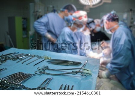 Closeup of surgical tools on table and team of surgery doctors operating a patient in hospital room Royalty-Free Stock Photo #2154610301