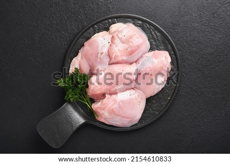 Raw chicken thigh fillet without skin with herbs and spices on black background. Farm poultry meat. Top view with copy space. Mock up. Royalty-Free Stock Photo #2154610833