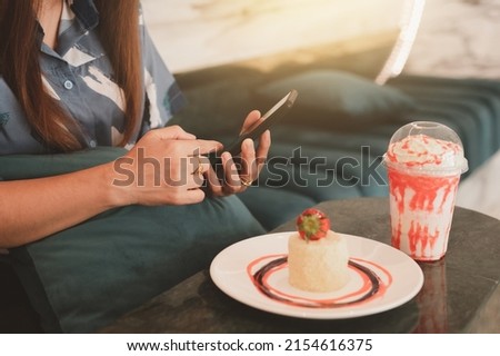 Woman preparing to photograph cakes and drinks, Piccolo Latte, brownies and breakfast on wooden table with smartphone.