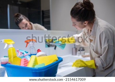 A young housewife cleaning in the bathroom