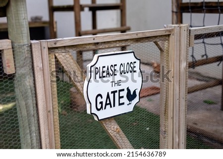 Please close the gate informative sign on mesh gate at poultry farm. unaltered, symbol and animal husbandry and farming industry concept.
