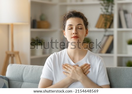 Calm beautiful young woman holding hands on her chest feeling grateful and thankful. Royalty-Free Stock Photo #2154648569