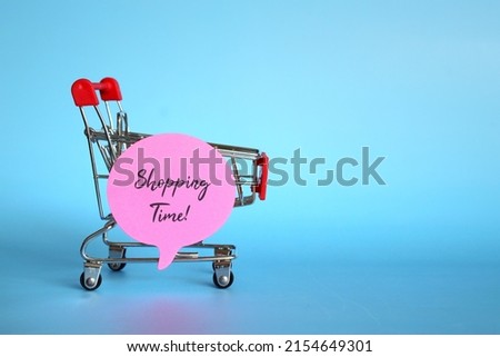 Shopping trolley and speech bubble with text SHOPPING TIME! on blue background with copy space