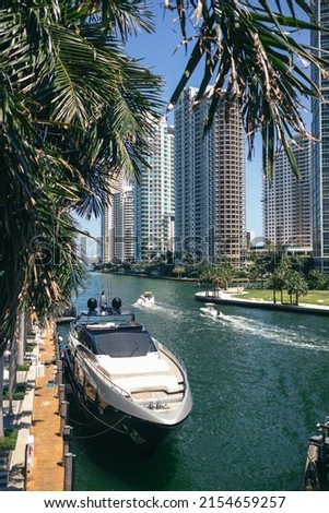 Yacht on Miami River, Florida on a sunny day under palm leafs 