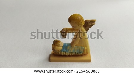 Ceramic figure of guardian messenger angel protect sleeping newborn baby Jesus Christ isolated on white background. lovely Vintage nativity scene figurine from Goebel. Close up macro top side view.