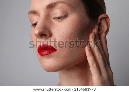 Close-up of beautiful young woman with glow skin and red lips make-up posing in the studio. Mock-up.
