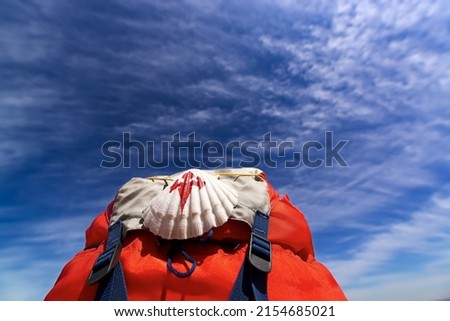 Way of St James , Camino de Santiago ,scallop shell on backpack with blue sky and clouds   to Compostela , Galicia, Spain Royalty-Free Stock Photo #2154685021