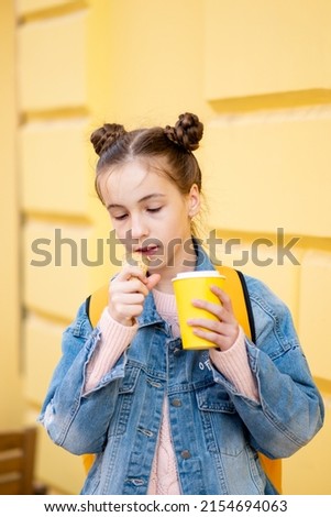 A cute girl eats ice cream and drinks tea outside. Takeaway. Happiness. Childhood. The concept of delicious food.