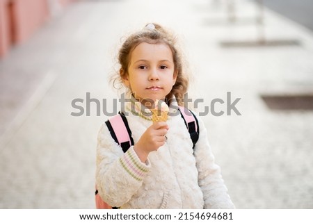 A cute little girl eats ice cream outside. Takeaway. Happiness. Childhood. The concept of delicious food.