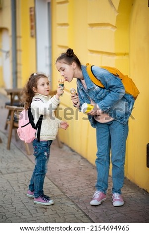 Two cute sister girls eats ice cream outside. Takeaway. Happiness. Childhood. The concept of delicious food.