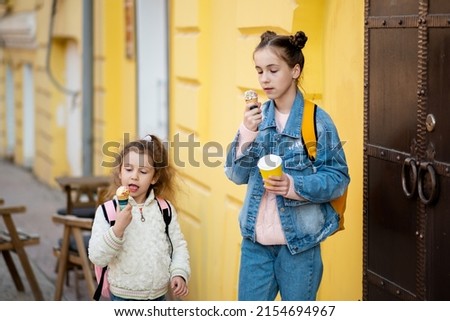 Two cute sister girls eats ice cream outside. Takeaway. Happiness. Childhood. The concept of delicious food.