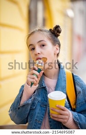 A cute girl eats ice cream and drinks tea outside. Takeaway. Happiness. Childhood. The concept of delicious food.