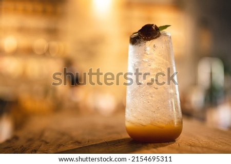 healthy cold drink of plum and honey soda with ice in glass, summer cocktail refreshment with tropical fruit juice are cool and fresh sweet with coffee cafe background