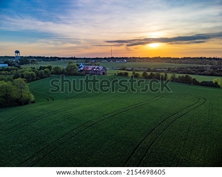 Sunset over agricultural fields in rural Kentucky between cities of Lexington and Nicholasville with a barn between tree lined pastures. Royalty-Free Stock Photo #2154698605