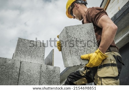 Hollow Dense Concrete Blocks Moved by Caucasian Construction Contractor Worker. Residential Construction. Royalty-Free Stock Photo #2154698851
