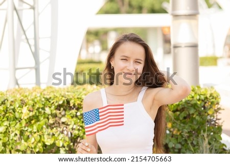 independence day,teenager girl waving the American flag, celebrating the holiday at barbecue picnics in the park