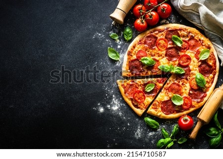 Traditional italian pizza with salami cheese, tomatoes and basil.