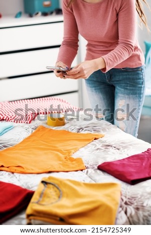 Woman taking pictures of her clothes on the bed, she wants to sell her second hand clothes online