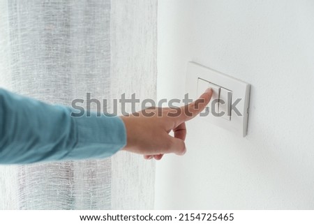 Woman pressing a light switch, energy saving concept Royalty-Free Stock Photo #2154725465