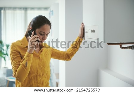 Worried woman calling a boiler breakdown emergency service using her smartphone Royalty-Free Stock Photo #2154725579