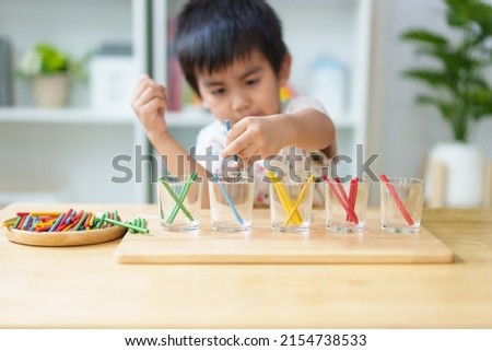 Blurred of asian 3 years old boy is learning to sorting the color rod to the glass, concept of homeschool, montessori, freedom, education, activity for child development and sensory activity for kid. Royalty-Free Stock Photo #2154738533