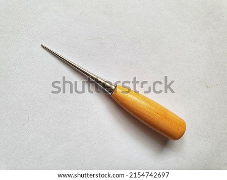 Leather craft awl with wood handle. A leather awl is a tool with sharp metal point used for marking, piercing, punching, or sewing leather and leather goods. Royalty-Free Stock Photo #2154742697