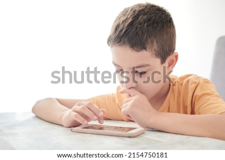 Primary school boy uses a mobile phone from early in the morning to play video games and watch videos on the internet. Problems of children addicted to screens.