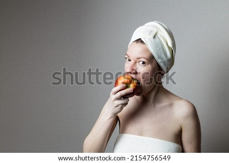 young woman after a bath in a towel. woman eats an apple.