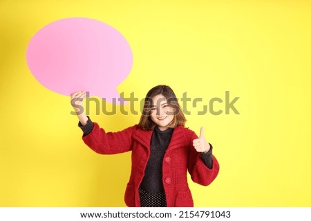 The chubby Asian woman standing on the yellow background with the casual clothes.