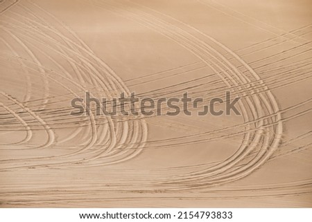 Tracks of cars on a sand dune create an abstract pattern of circles that are crossing each other. Creating a sense of feeling lost, driving in circles. Presentation background or symbol picture. 