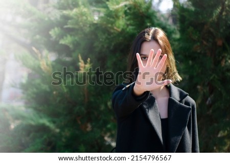 The girl on the street covers her face with her palm. Gesture of denial, termination, protest. Place for text, copyspace.