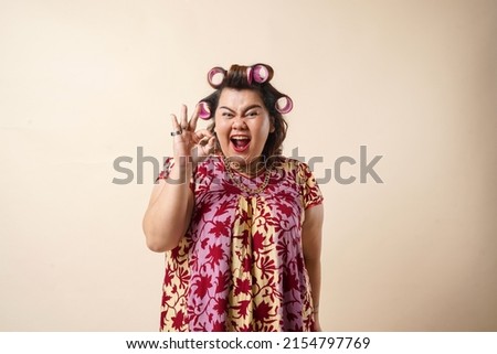 An Asian woman gesturing okay sign using her hand. Isolated on cream background.  Royalty-Free Stock Photo #2154797769