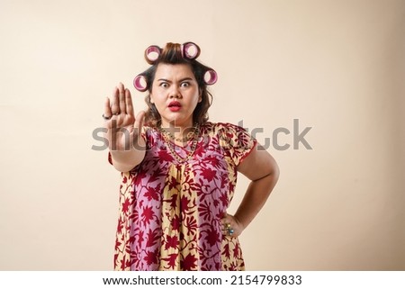 An Asian woman gesturing stop sign using her hand. Isolated on cream background. 