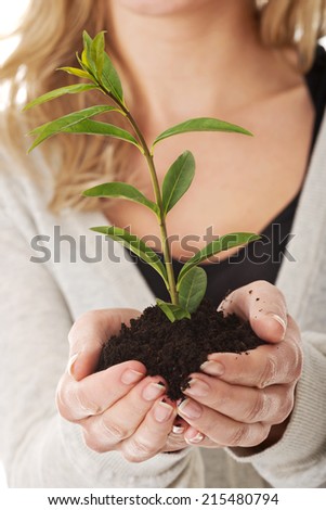 Happy woman with plant and dirt in hand