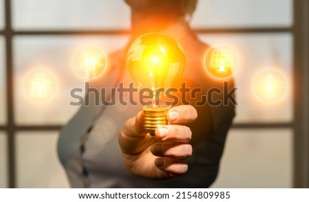 Concept of energy saving, rational use of natural resources and development of renewable energy sources. Woman in hand holding light bulb with electricity generation icons Royalty-Free Stock Photo #2154809985
