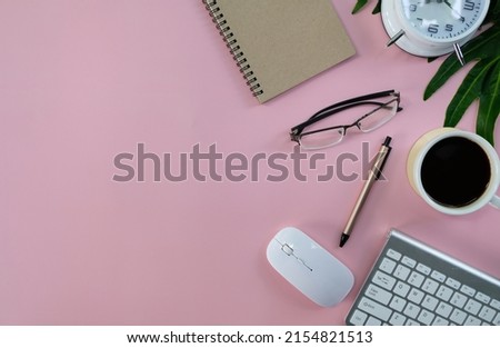 Blank notebook with pen are on top of white office desk table with laptop computer, cup of latte coffee and supplies. Top view with copy space, flat lay