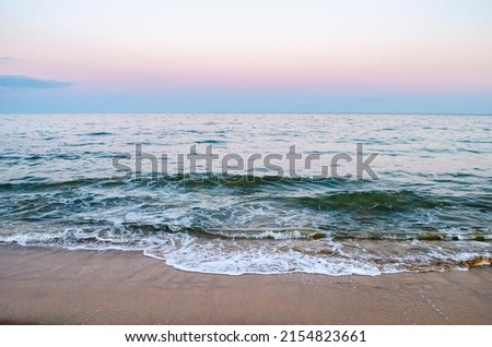 Summer evening at the seashore. View of the soft sea wave on the sandy beach.