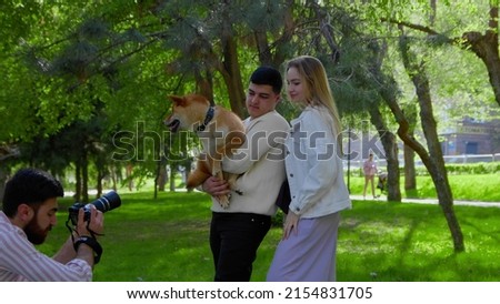 The photographer takes a picture of a young family with a dog in nature. Photo shoot in nature