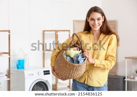 Beautiful housewife holding wicker basket with laundry at home Royalty-Free Stock Photo #2154836125