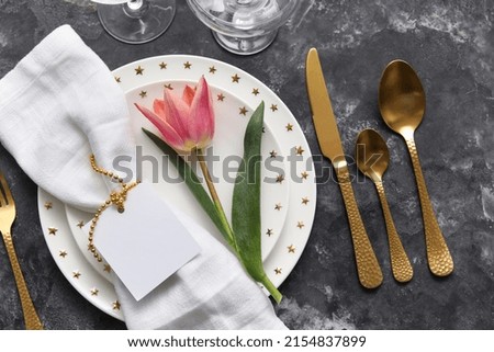 Table setting with tulip and blank card on grunge background