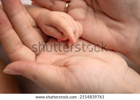 The palm of a newborn baby in the palms of the parents