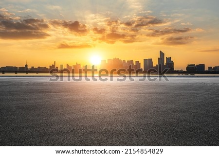 Asphalt road and modern city skyline with buildings in Hangzhou at sunset, China.