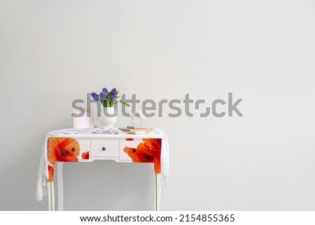 Stylish table with fresh hyacinth flowers in vase near light wall in room